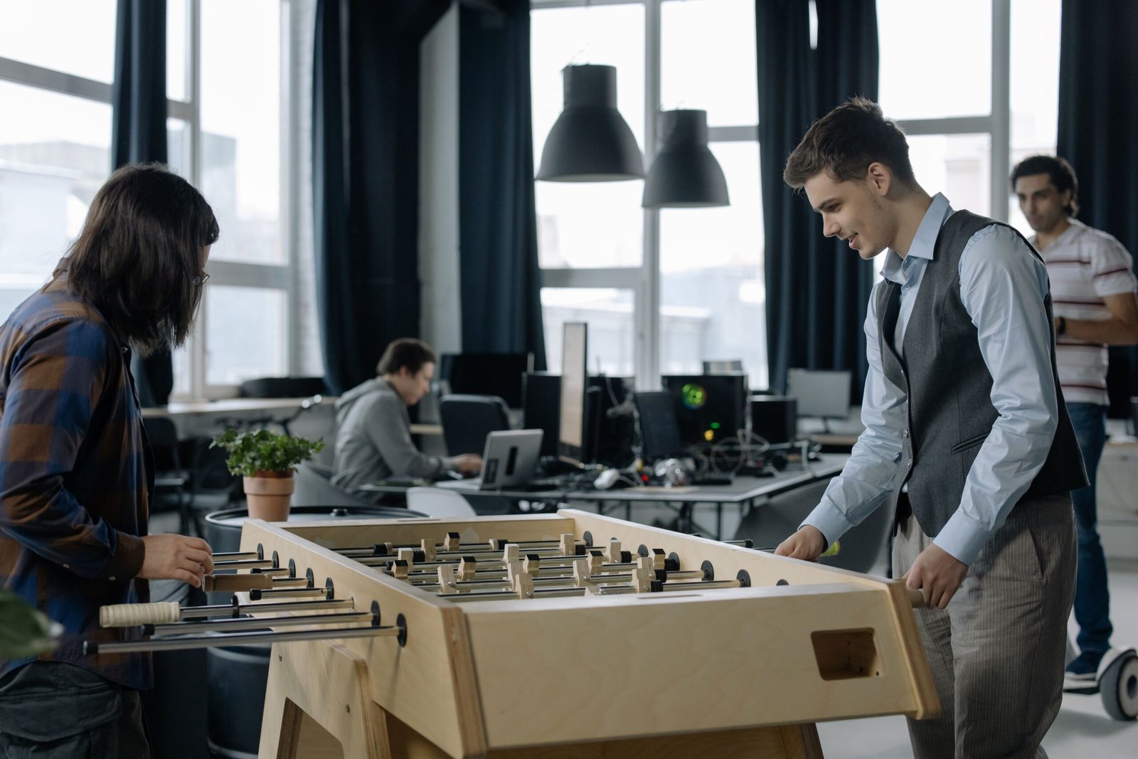 Office workers taking a break to play foosball in a modern startup environment.